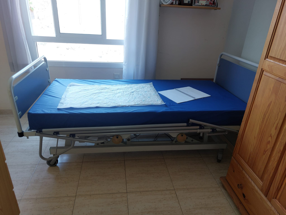 Cama hospitalaria montada junto a una ventana, vista lateral completa